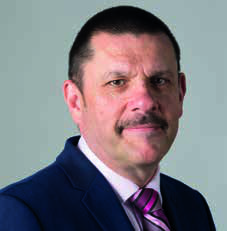 Portrait of a man with a mustache in a dark suit and pink striped tie.