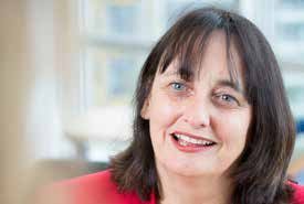 Close-up portrait of a smiling woman with dark hair and a red top, looking slightly to the right.