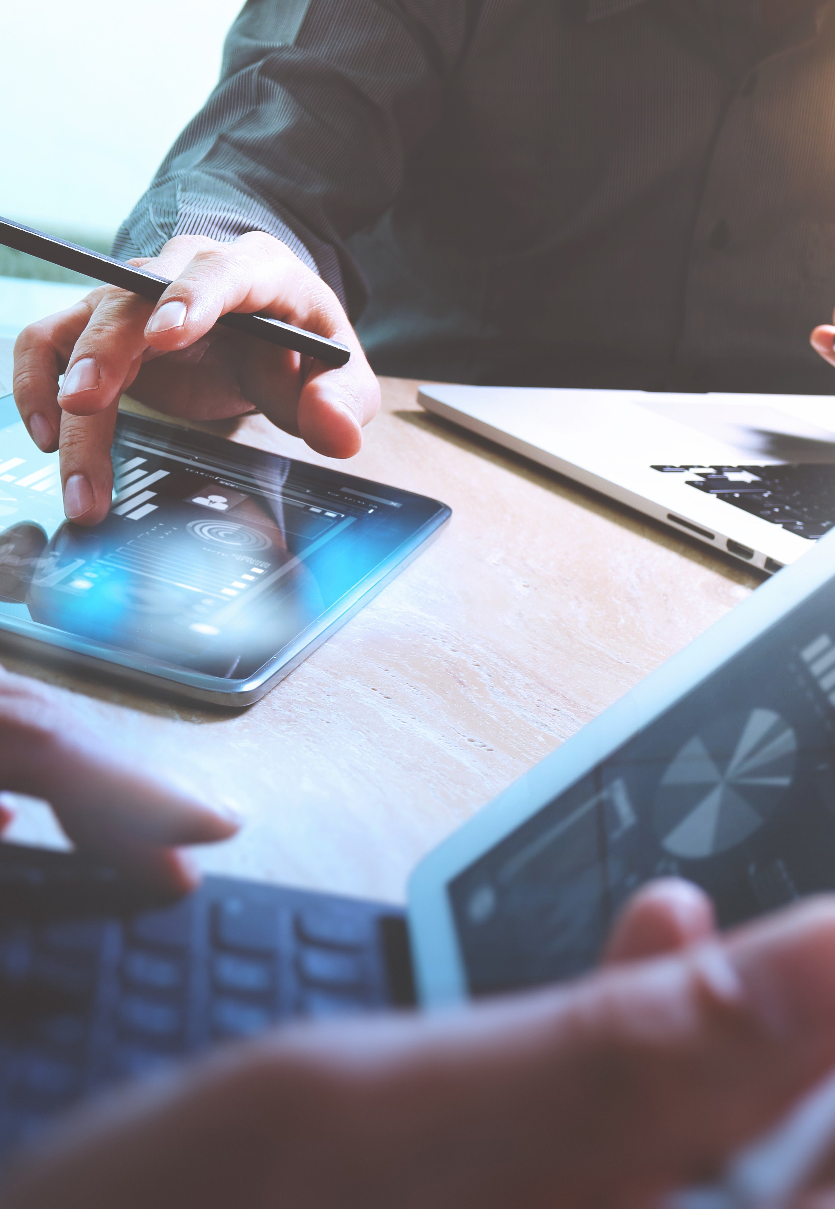 Hands working on laptops and tablets, displaying various data visualizations and charts, indicating collaborative data analysis.