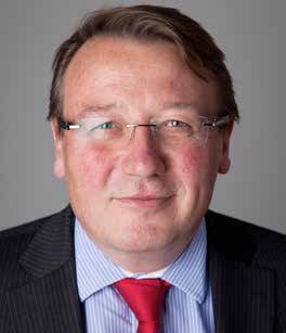 Headshot of a middle-aged man with glasses, wearing a striped shirt and red tie.