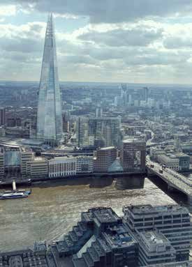 Panoramic view of The Shard skyscraper towering over the London skyline and the River Thames on a cloudy day.