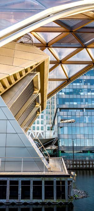 Dynamic view of contemporary buildings with complex glass and geometric designs, set against a waterway.