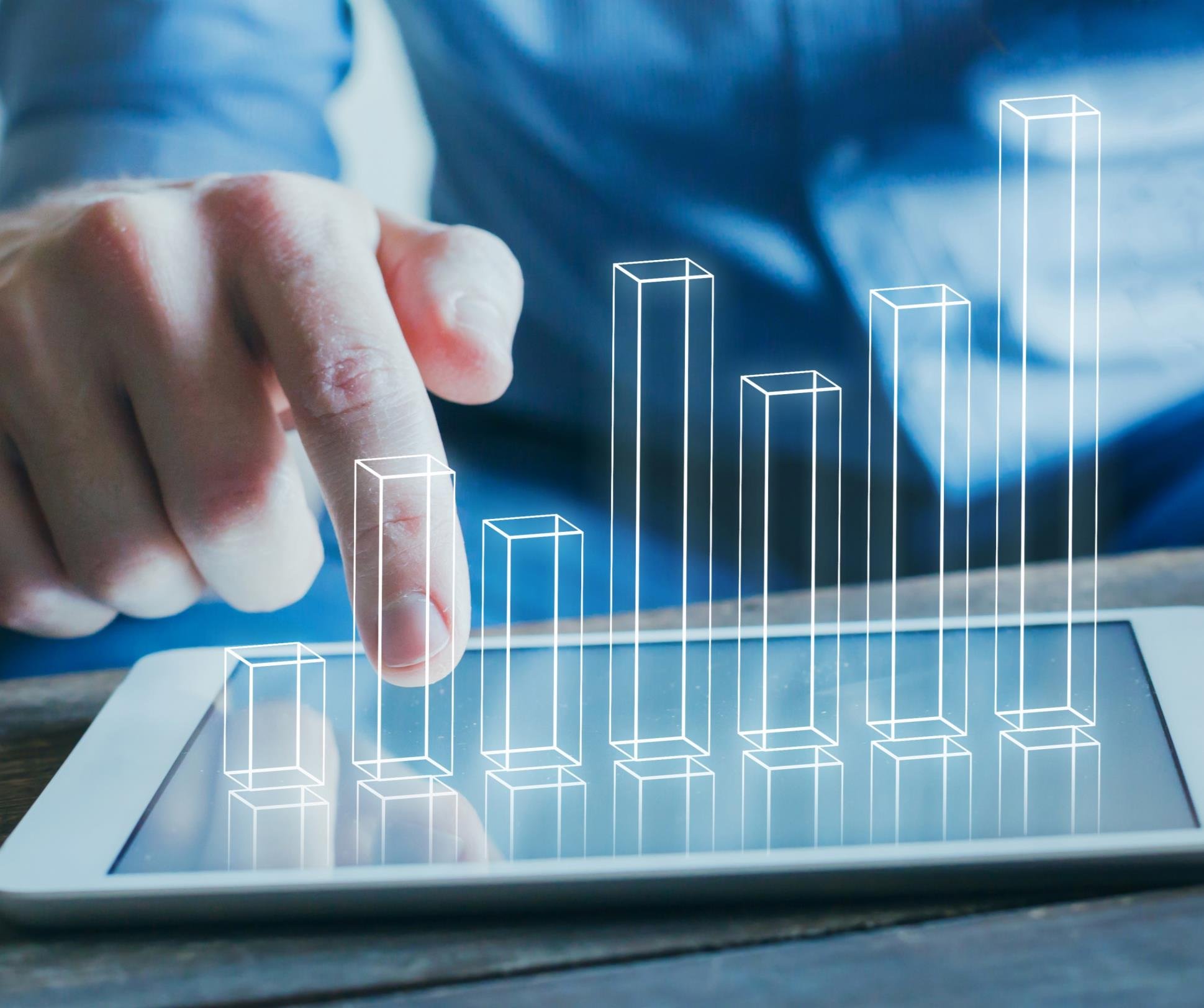 Hand interacting with a tablet displaying a conceptual 3D bar chart on the screen, representing data visualization or growth.