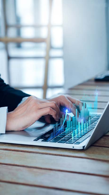Hands typing on a laptop, with blue holographic bar graphs and an upward arrow indicating data analysis and business growth.
