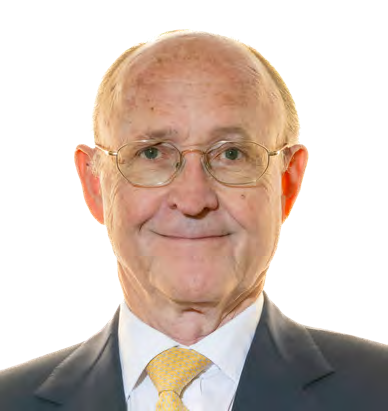 Headshot of an older man with glasses, grey hair, and a yellow patterned tie, smiling.