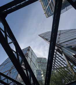 View looking up through a dark metal structural frame at modern glass skyscrapers against a blue sky.