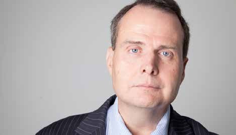 Headshot of a middle-aged man with blue eyes, wearing a pinstripe jacket over a blue shirt.