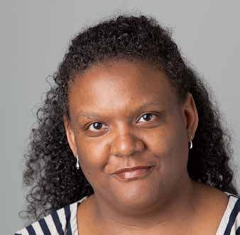 Headshot of a woman with dark curly hair and earrings, smiling.