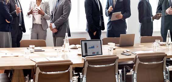 Business professionals in a meeting with a laptop displaying bar and pie charts on a conference table, indicating data discussion.