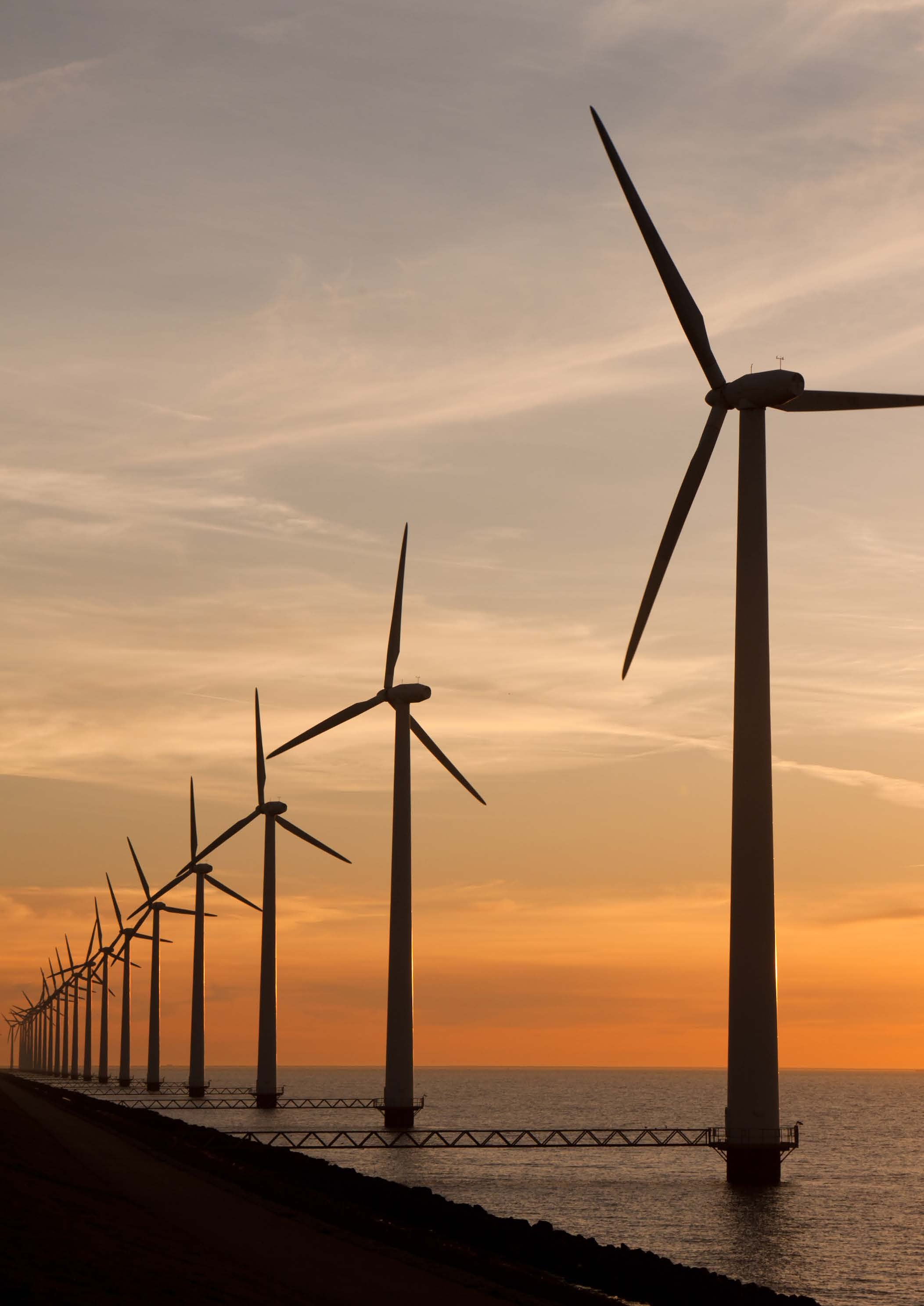 Row of wind turbines in the sea at sunset, representing renewable energy or sustainable infrastructure.