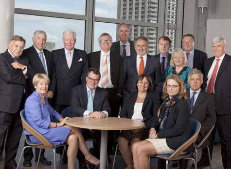 Group photo of a professional team or board of directors, including men in suits and women in business attire, posing indoors.
