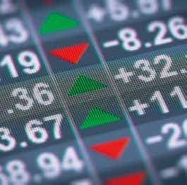 Close-up of a digital display showing financial data with numbers, green up arrows, and red down arrows, indicating market performance.