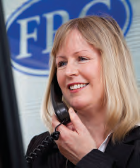 Smiling woman with blonde hair talking on a black telephone receiver, with a blurred FRC logo in the background.