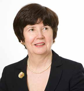 Headshot of a woman with short dark hair, wearing a pearl necklace and a broach.