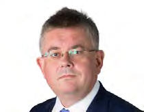 Headshot of a man with glasses and dark hair wearing a suit and blue tie.