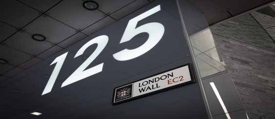 Close-up of building numbers "125" and a sign for "London Wall EC2" with the City of London crest.