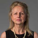 Headshot of a blonde woman wearing a black top and a pearl necklace.