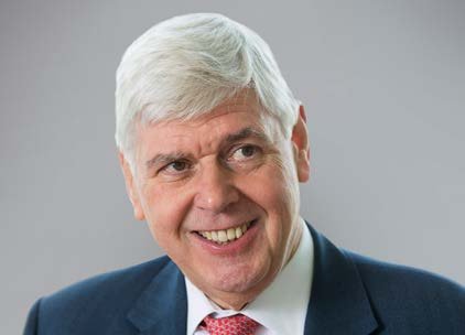 Portrait of a smiling man with white hair, wearing a suit and tie.