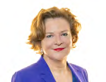 Headshot of a woman with auburn hair and red lipstick wearing a blue blazer.