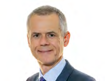 Headshot of a man with short grey hair wearing a suit and patterned tie.
