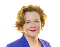 Headshot of a woman with curly auburn hair, pearl earrings, and red lipstick.