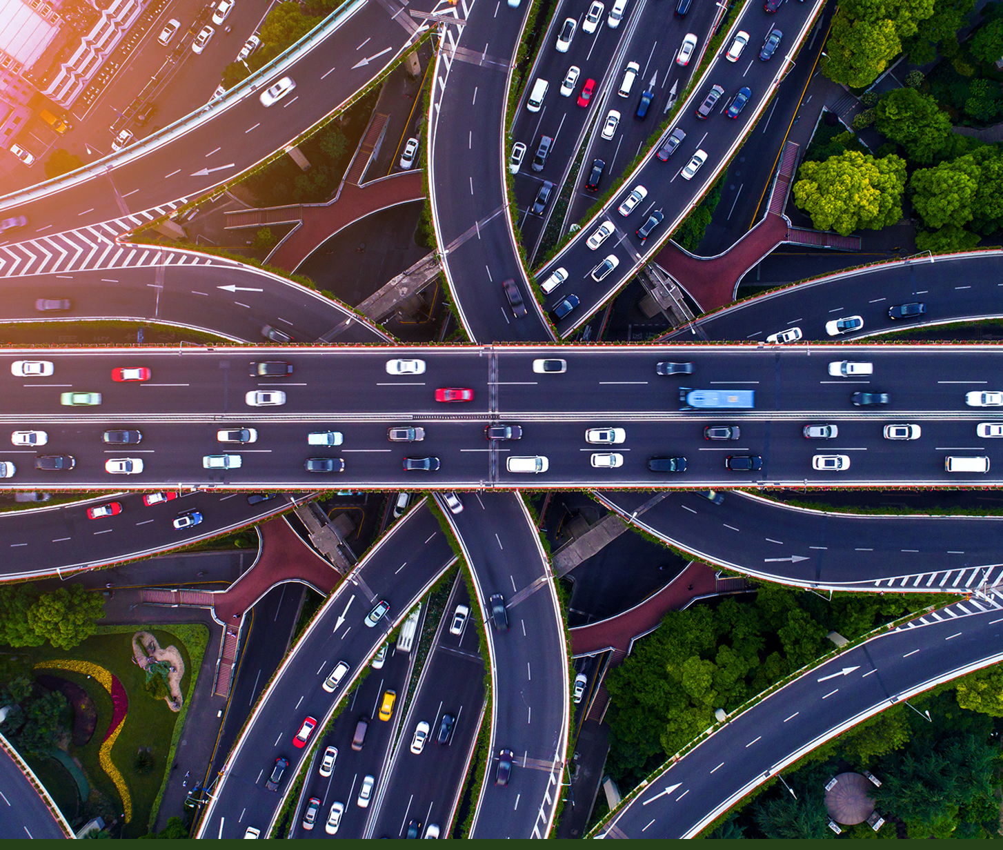 Aerial view of a multi-level highway interchange with numerous cars traversing complex ramps and bridges, showing urban infrastructure and traffic flow.