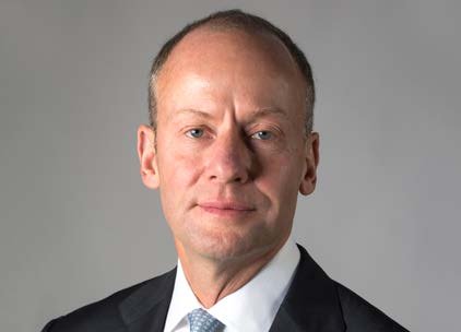Portrait of a man with short brown hair, wearing a dark suit and a light blue tie.