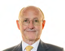 Headshot of an older man with glasses, smiling, in a suit and yellow tie.