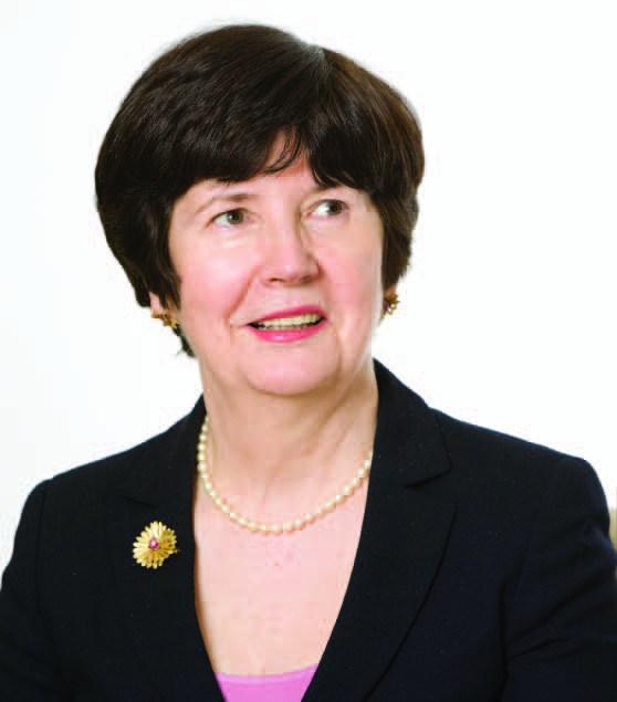 Portrait of a professional woman with short dark hair, wearing a suit and pearl necklace.