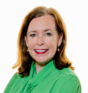 Headshot of a smiling woman with brown hair, wearing a green blouse and pearl earrings.
