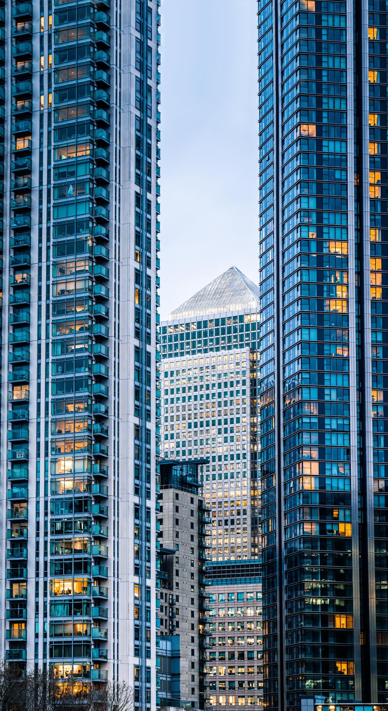 Modern high-rise buildings with many windows, some lit up, in an urban environment.