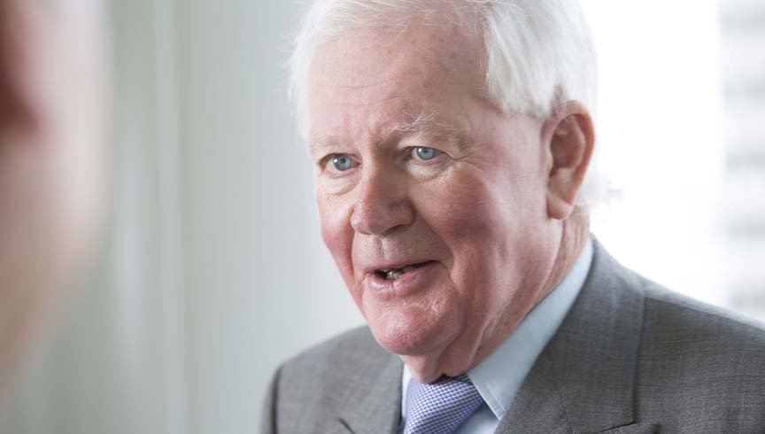 Portrait of an older man with white hair, wearing a suit and light blue tie, looking to the right.