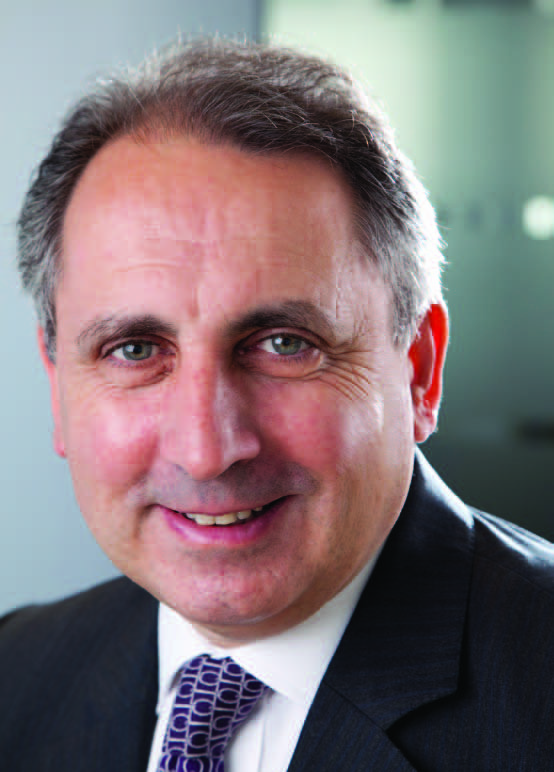 Close-up portrait of a professional man smiling, wearing a suit and patterned tie.